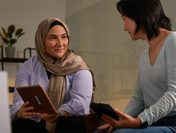 Due persone del team Machine Learning & AI di Apple che lavorano insieme: una tiene in mano un iPad e l’altra un iPhone.