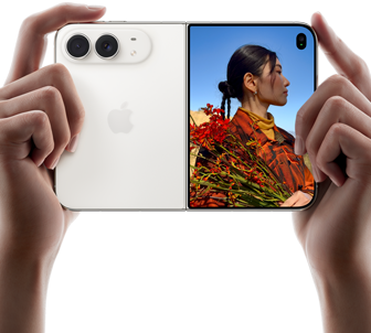 iPhone Duo, tähesära värvitoonis, hoitakse kahe käega horisontaalasendis, lahtivolditult, vasak paneel näitab 48MP Dual Fusion tagakaameraid, parem paneel näitab inimest, kellest tehakse fotot välisel ekraanil, foto subjekt näeb oma nägu, kui temast tehakse pilti Duo eelvaate abil