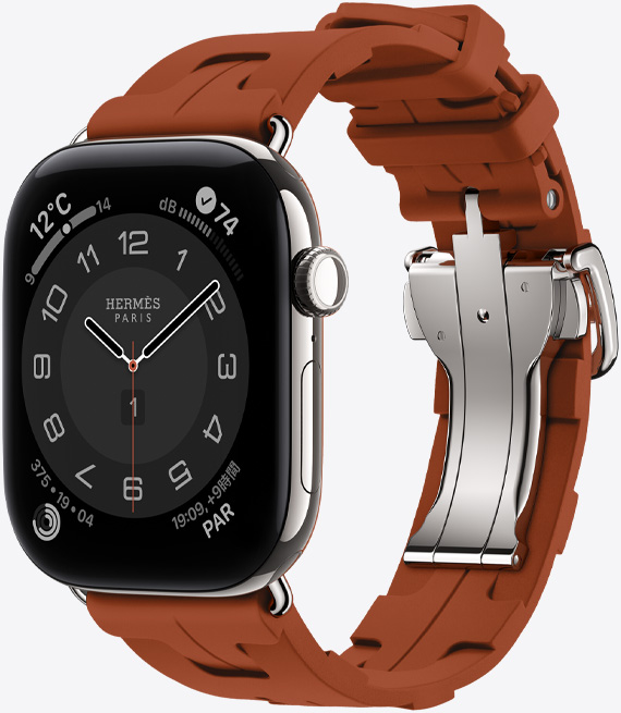 シルバーチタニウムケースのApple Watch Hermès Series 12、アナログデザインのCirculaireの文字盤に、時針、分針、秒針と、天気、ノイズ、アクティビティリング、パリの時間のコンプリケーションが表示されている。右側面の外観、Digital Crown、サイドボタン。キュイーヴル（ブラウン）のキリムシンプルトゥールストラップとの組み合わせ。成形ラバー素材、幾何学的に連なるデザイン、シルバーのメタルクラスプ