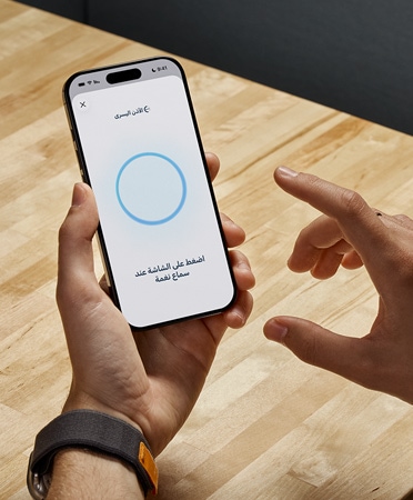 يحمل أحد مستخدمي سماعات AirPods Pro 2 جهاز iPhone أثناء استخدام ميزة اختبار السمع الجديدة