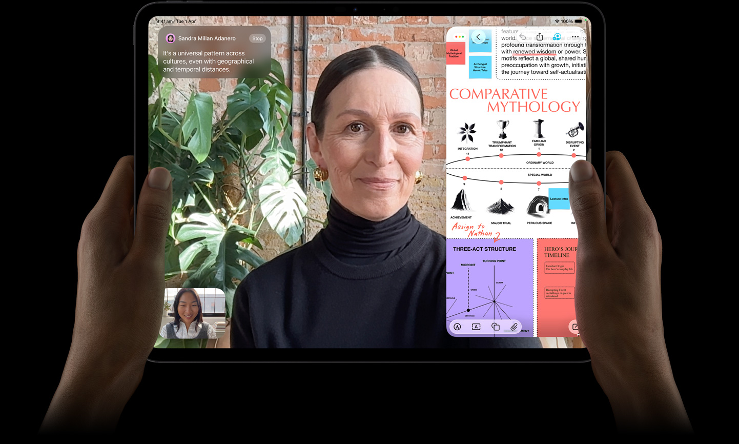 iPad Pro, front exterior, space black colour, left and right hands holding in landscape orientation, rounded corners, black display bezel, display showing a FaceTime conversation being live translated, and an educational app showing a presentation of ‘Comparative Mythology' with text, diagrams and handwritten notes