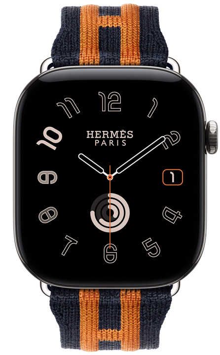 Apple Watch Hermès Series 12, quadrante analogico Radial (lancette dell’ora, dei minuti e dei secondi, complicazioni: data, anelli Attività), cassa in titanio color argento, lato destro, Digital Crown, tasto laterale in rilievo, cinturino Rocabar Club color Bleu Nuit/Orange in tessuto a maglia blu scuro con motivo a strisce arancioni in rilievo che formano la H di Hermès