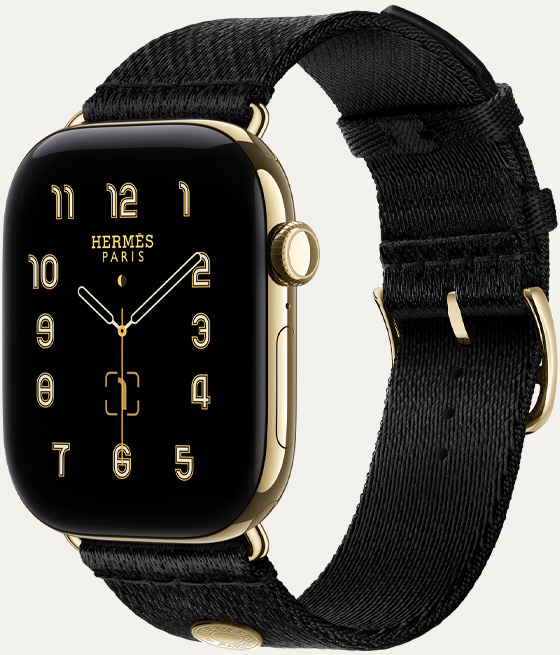Apple Watch Hermès Series 12, quadrante analogico Clou de Selle (lancette dell’ora, dei minuti e dei secondi, complicazioni: fase lunare, data), cassa in titanio color oro brillante, lato destro, Digital Crown, tasto laterale, cinturino Satin Clou de Selle color Noir in tessuto satinato nero liscio con chiusura e anse color oro brillante coordinate alla cassa