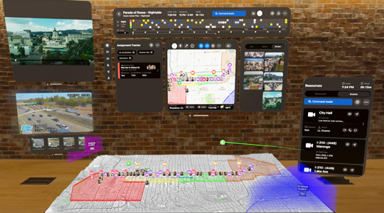 A 3D projection of dashboards for firefighters shows camera feeds, team assignments and a 3D model of a mountain, in front of a window inside an office
