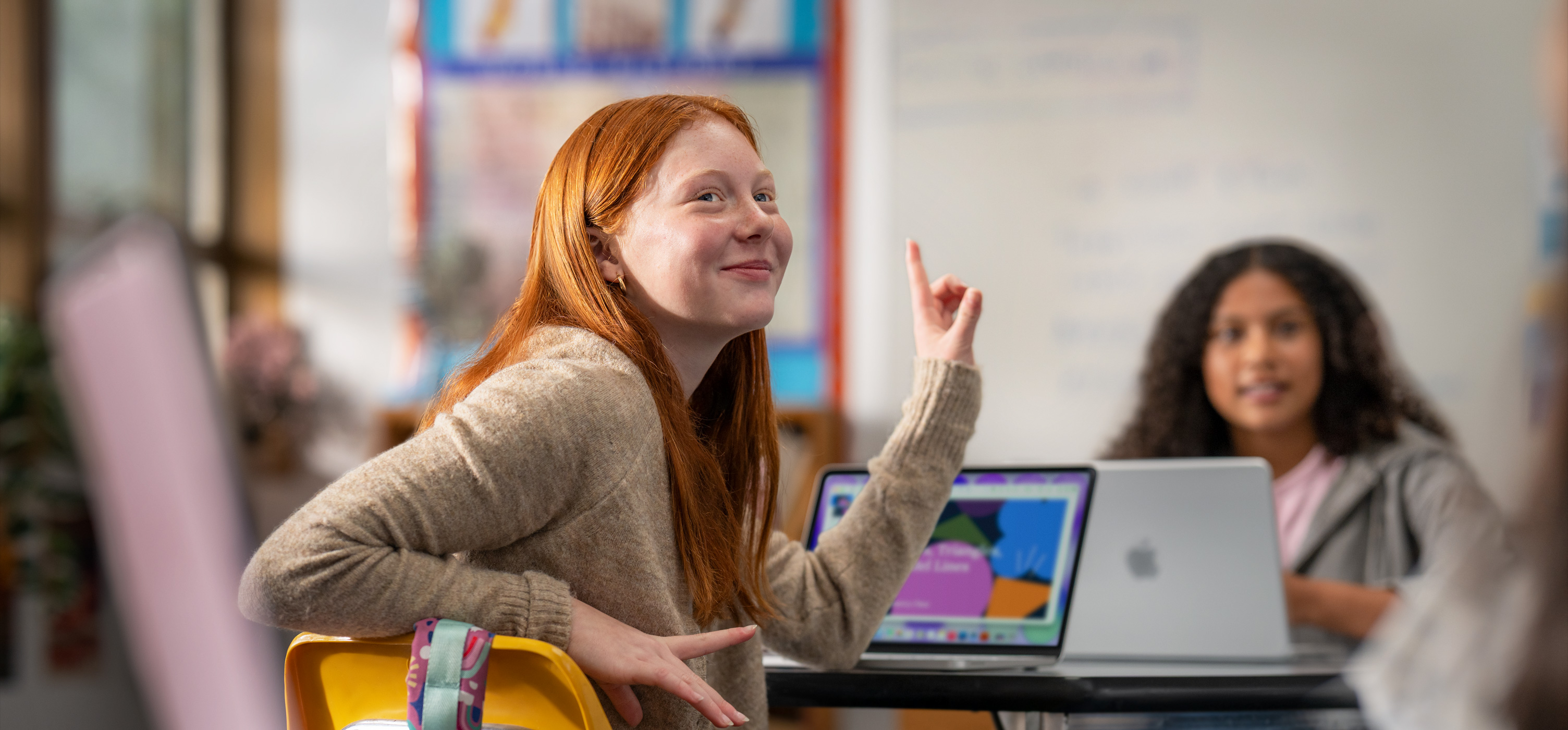 Studente davanti a un MacBook in classe, che alza la mano per rispondere a una domanda, suggerendo la facilità d’uso e di coinvolgimento