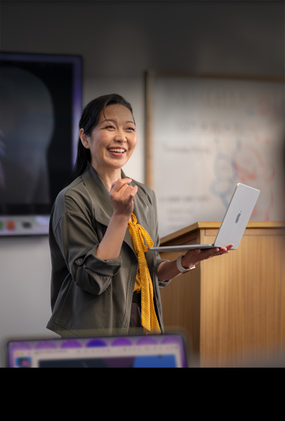 Docente che fa lezione in un’aula universitaria con in mano un MacBook color argento per dimostrare le prestazioni e la lunga autonomia del dispositivo