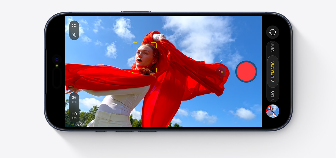 Écran d’iPhone montrant le mode Cinématique en cours d’utilisation pour filmer une personne qui danse dehors avec un foulard rouge