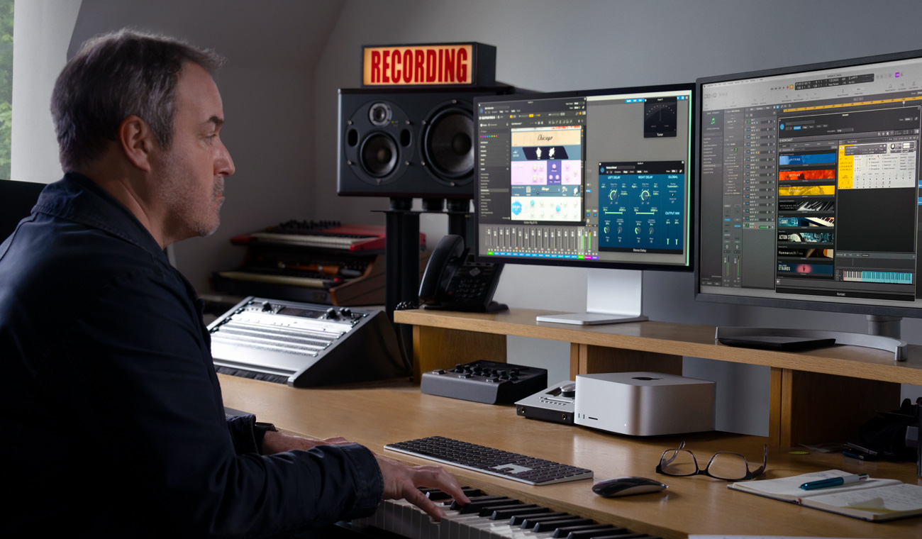 A musician using a piano to create audio mixes with Mac Studio and Studio Display