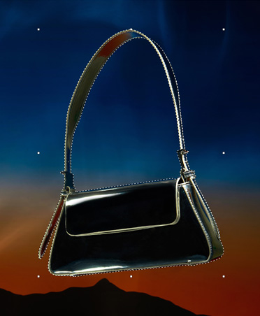 A black purse that is outlined with dashed lines, selection tool, editing image, sunset background with silhouette of mountains